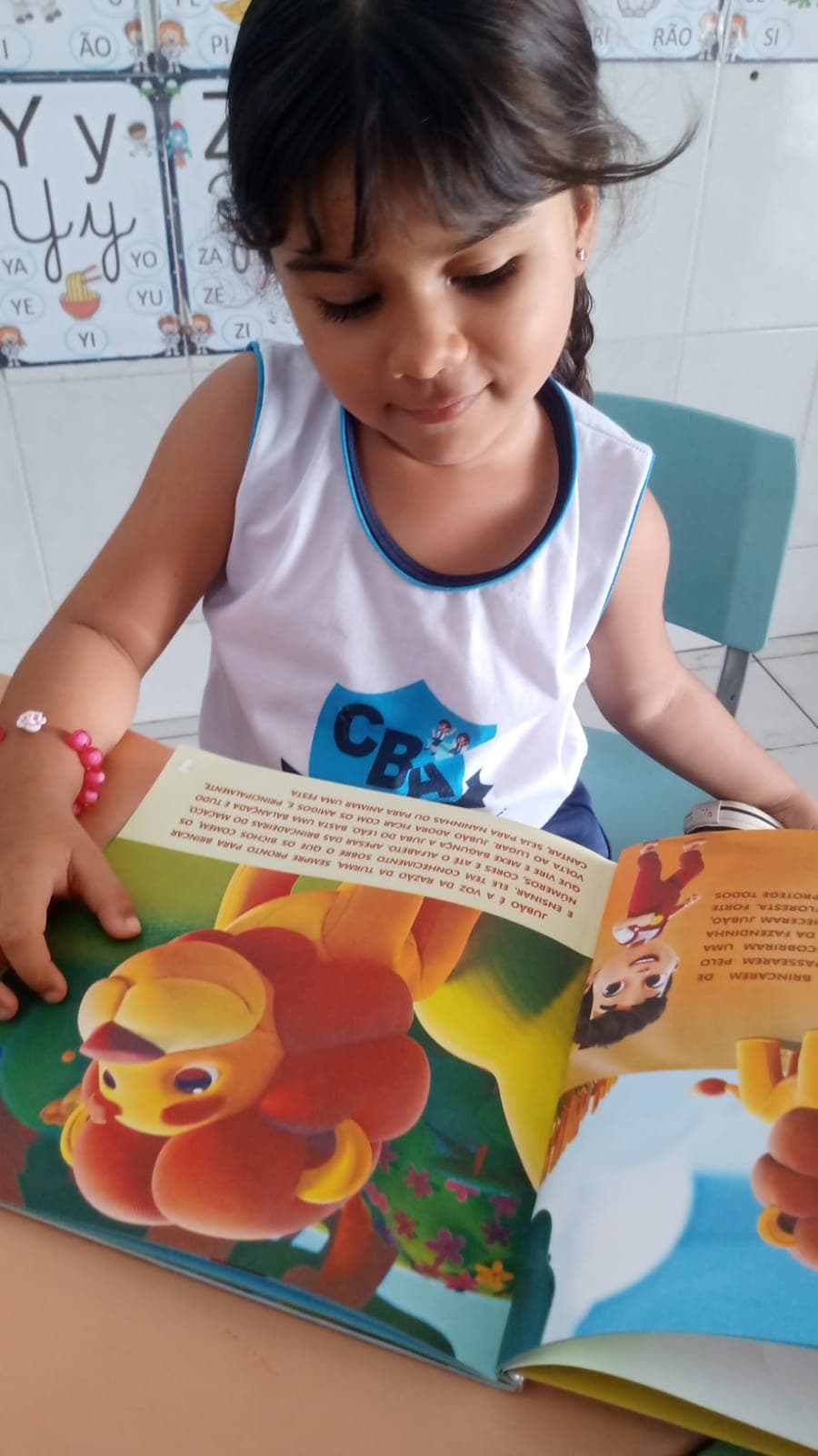 Criança sorrindo durante atividade de leitura e alfabetização em sala do Colégio Baby Avançar
